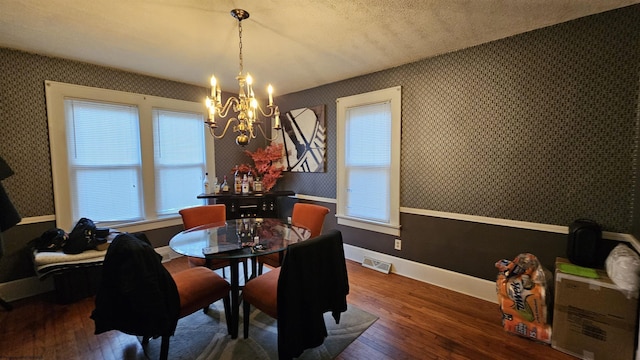 dining area with a notable chandelier, visible vents, baseboards, dark wood-style floors, and wallpapered walls