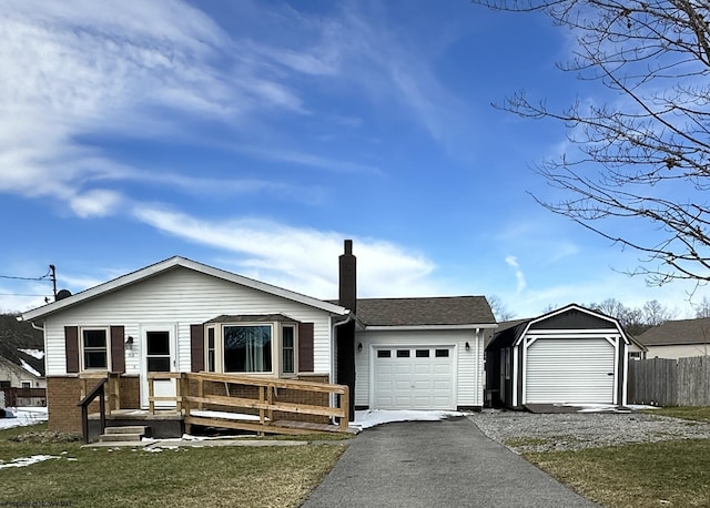 view of front facade with a garage, a chimney, aphalt driveway, roof with shingles, and fence