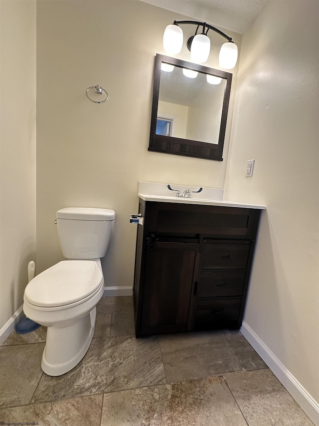 bathroom with baseboards, vanity, and toilet