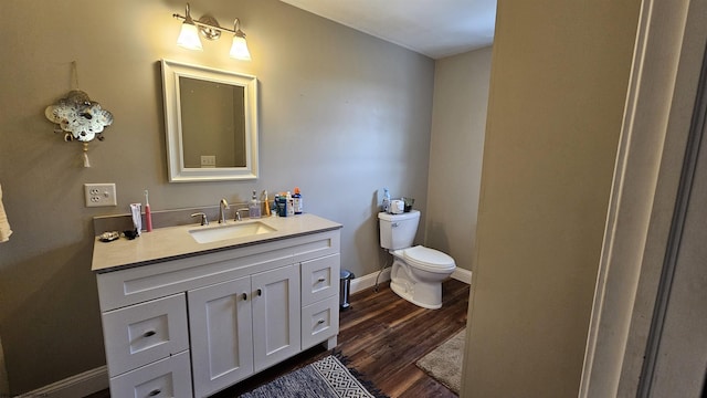 bathroom with toilet, baseboards, wood finished floors, and vanity