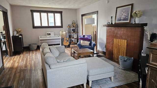 living area featuring a textured ceiling, wood finished floors, and baseboards