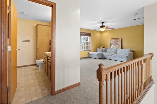 living room with attic access, baseboards, a ceiling fan, and light colored carpet