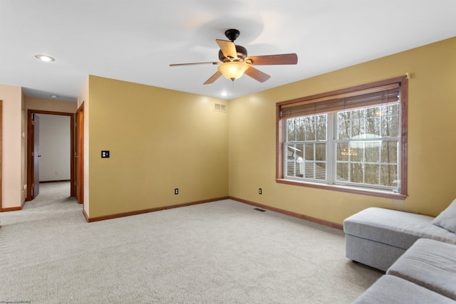 living room featuring a ceiling fan, visible vents, light carpet, and baseboards