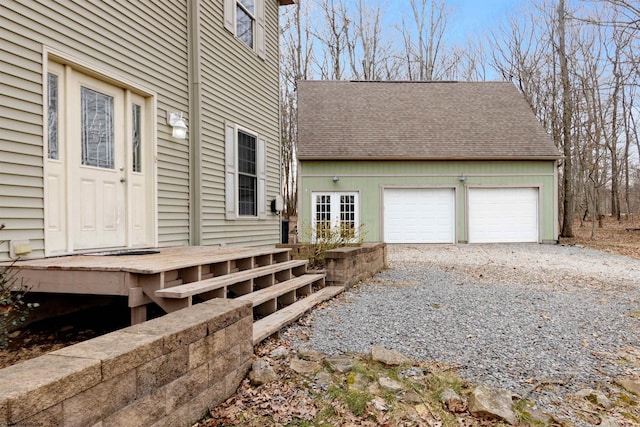 exterior space featuring gravel driveway, a shingled roof, and a garage