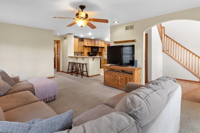 living room with arched walkways, stairway, visible vents, and light colored carpet