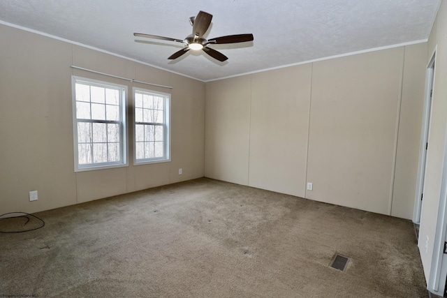 carpeted spare room with ornamental molding, visible vents, a textured ceiling, and a ceiling fan