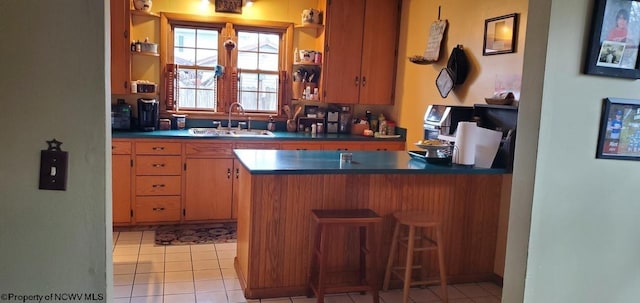 kitchen with open shelves, dark countertops, a sink, and a peninsula
