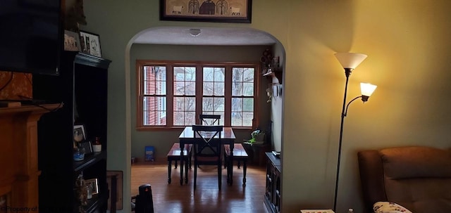 dining room featuring arched walkways and dark wood-style flooring