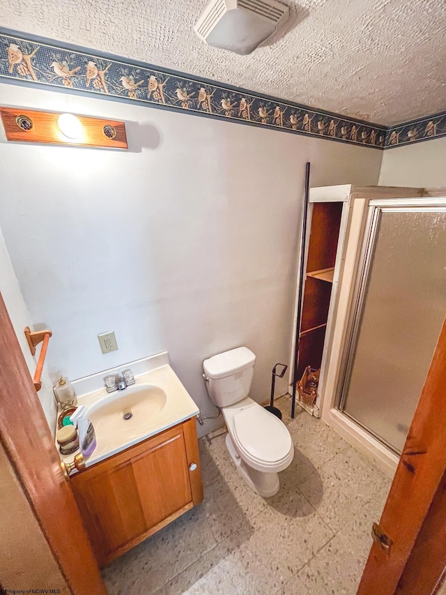 bathroom with toilet, a shower stall, a textured ceiling, vanity, and tile patterned floors