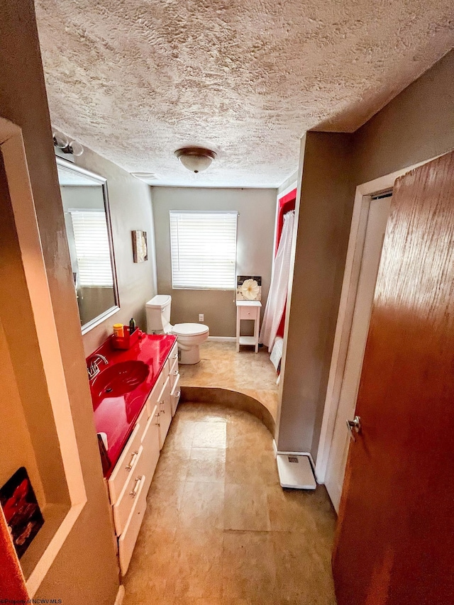 bathroom featuring toilet, a textured ceiling, and vanity