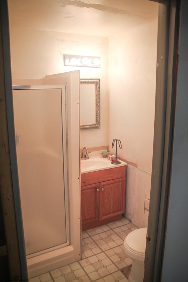 bathroom with a shower stall, a wainscoted wall, vanity, and toilet