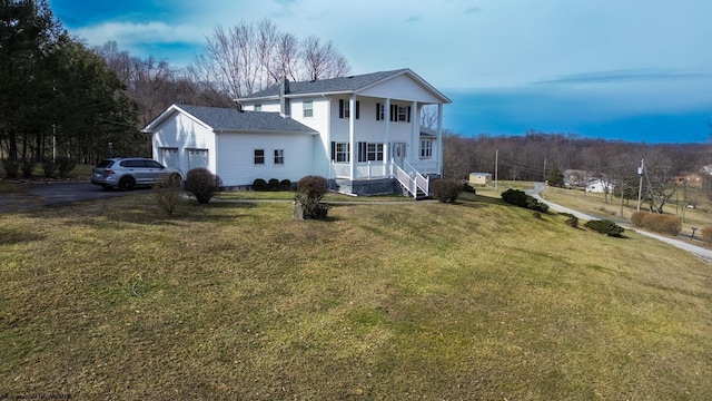 rear view of house featuring a garage, covered porch, aphalt driveway, and a yard