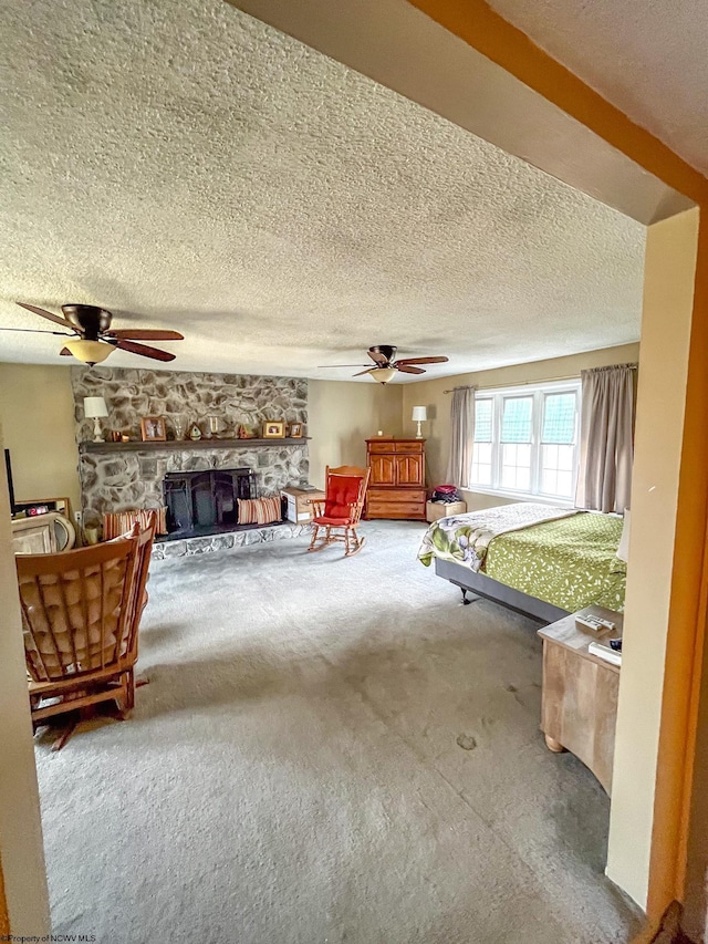 unfurnished bedroom with carpet floors, a stone fireplace, a textured ceiling, and a ceiling fan