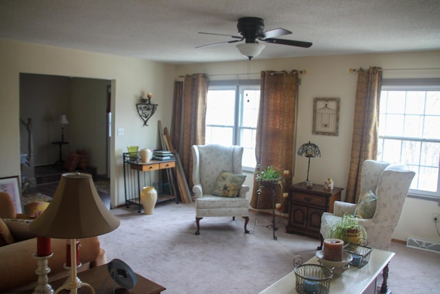 living room featuring carpet floors, a textured ceiling, visible vents, and a wealth of natural light