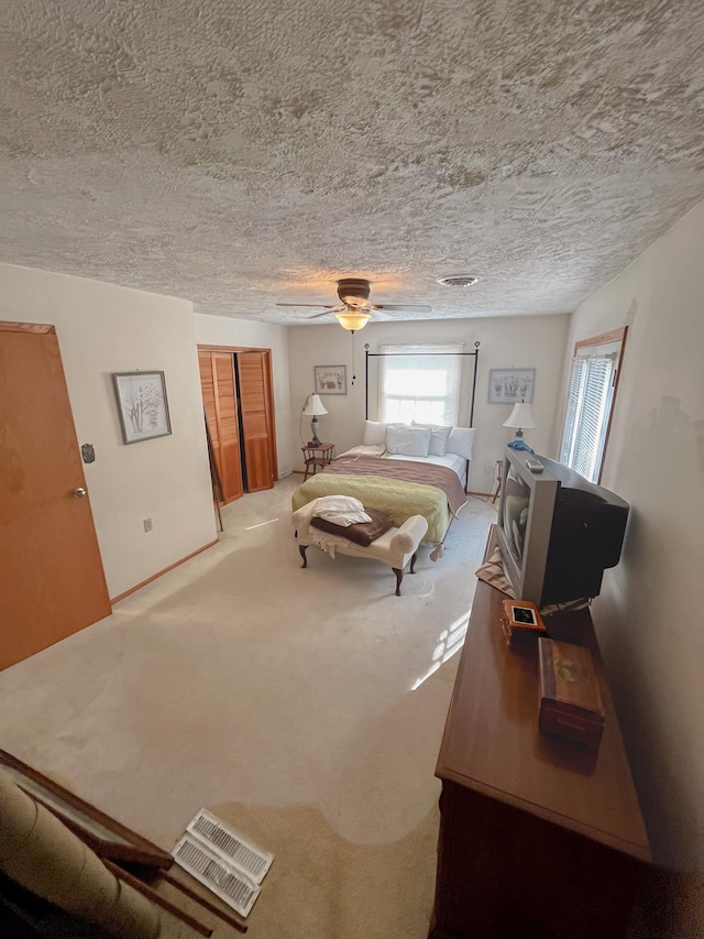 bedroom with visible vents, ceiling fan, carpet, a textured ceiling, and a closet