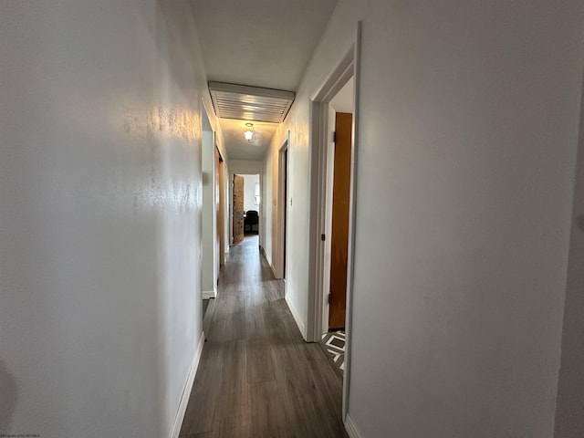 corridor with dark wood-style flooring and baseboards