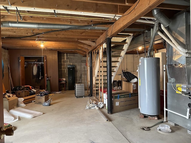 unfinished basement with gas water heater, heating unit, and stairs