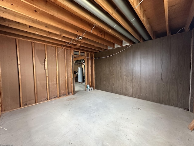 unfinished basement with wood walls and gas water heater