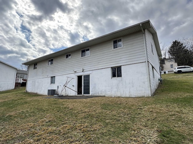 rear view of property featuring a lawn and cooling unit