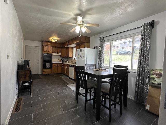 dining room featuring a ceiling fan, dark tile patterned flooring, visible vents, and baseboards