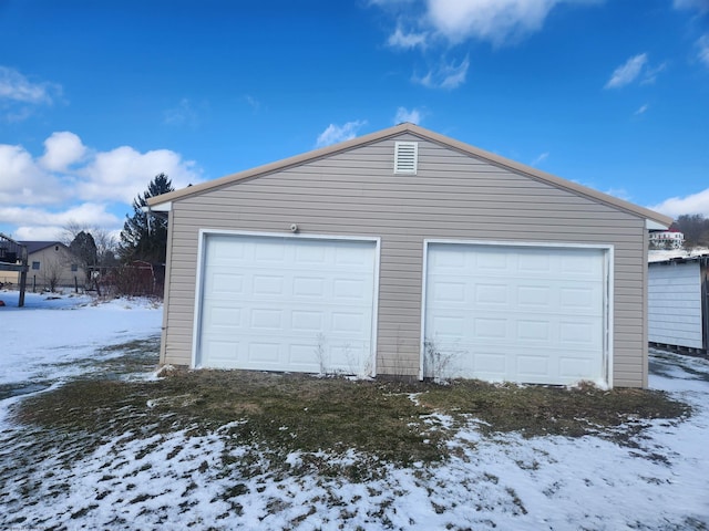 snow covered garage with a detached garage