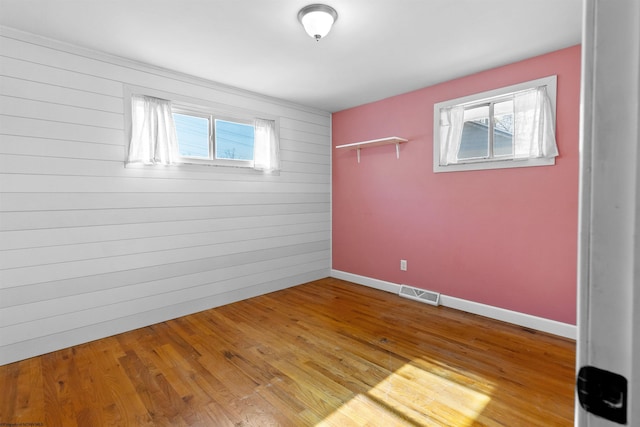 empty room with baseboards, light wood-style flooring, visible vents, and a wealth of natural light