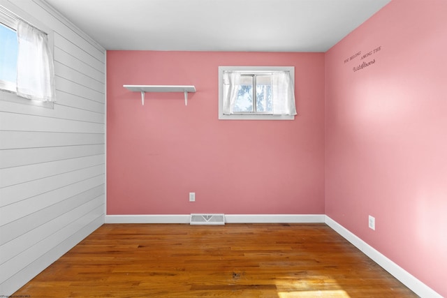 spare room featuring wood finished floors, visible vents, and baseboards