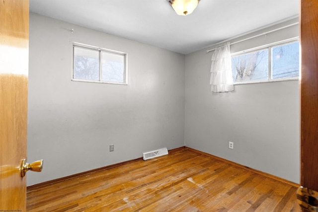 empty room featuring wood finished floors, visible vents, and baseboards