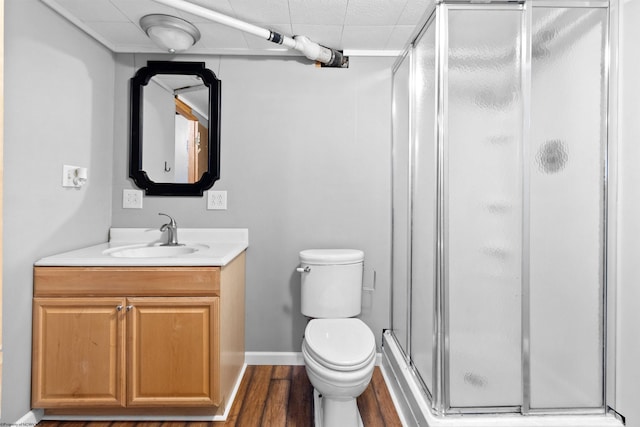 full bath featuring toilet, a stall shower, vanity, wood finished floors, and baseboards