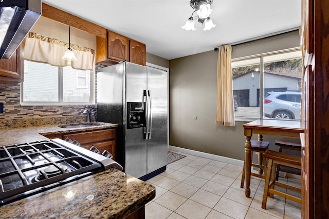 kitchen featuring light tile patterned floors, stainless steel fridge with ice dispenser, backsplash, a sink, and baseboards