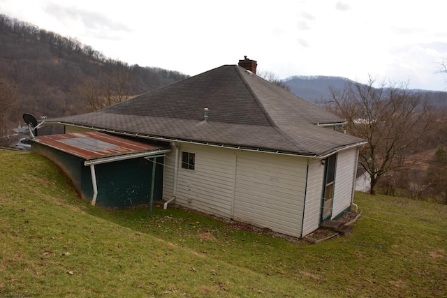 view of home's exterior featuring roof with shingles, a yard, and a chimney