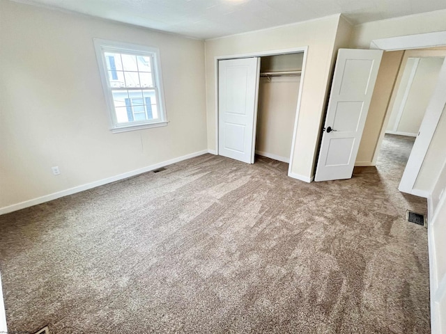 unfurnished bedroom featuring carpet, a closet, visible vents, and baseboards