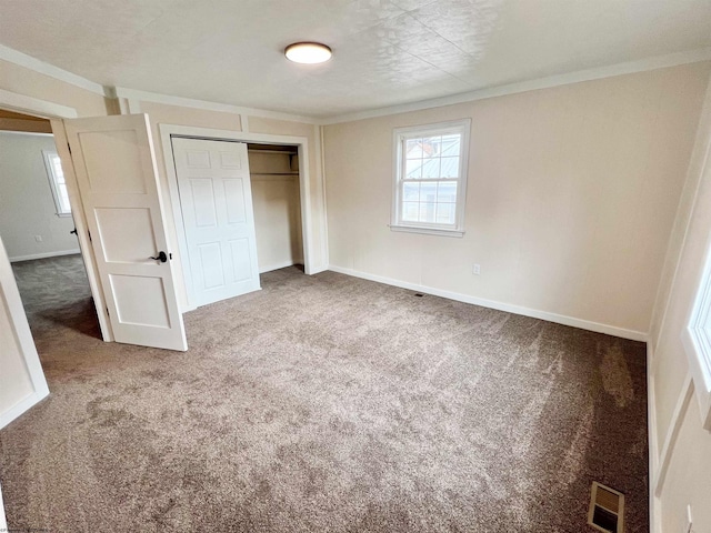 unfurnished bedroom featuring baseboards, carpet, visible vents, and a closet