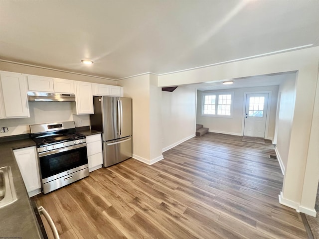 kitchen featuring white cabinets, dark countertops, light wood-style flooring, stainless steel appliances, and under cabinet range hood