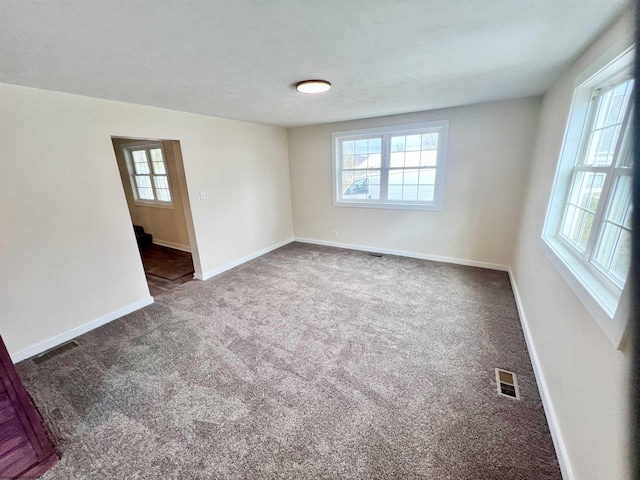 spare room with carpet, visible vents, and baseboards