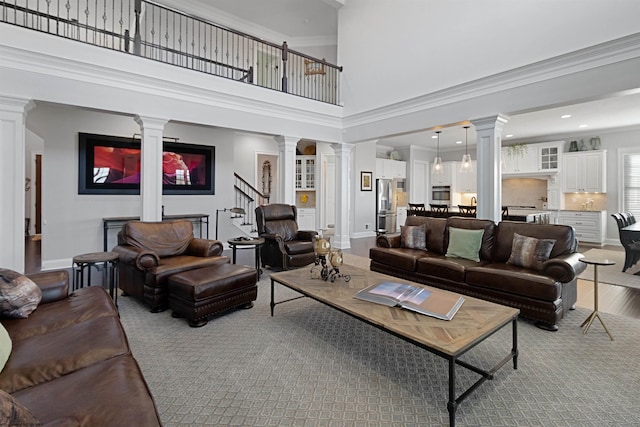 living room with ornate columns, stairs, baseboards, and crown molding