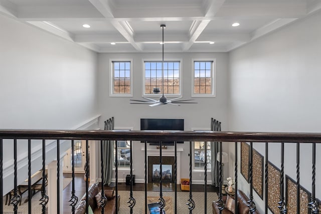 stairs featuring a ceiling fan, a wealth of natural light, beam ceiling, and wood finished floors