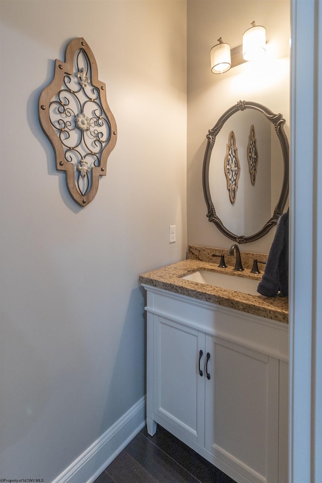 bathroom with wood finished floors, vanity, and baseboards