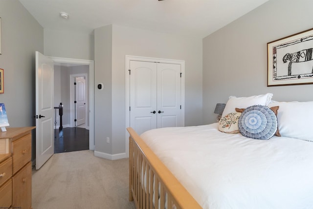 bedroom with baseboards, a closet, and light colored carpet