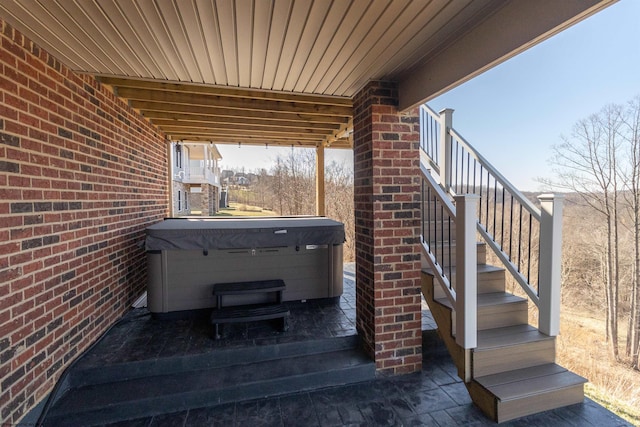 view of patio / terrace with a hot tub and stairs