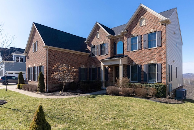 traditional home featuring central air condition unit, brick siding, and a front yard