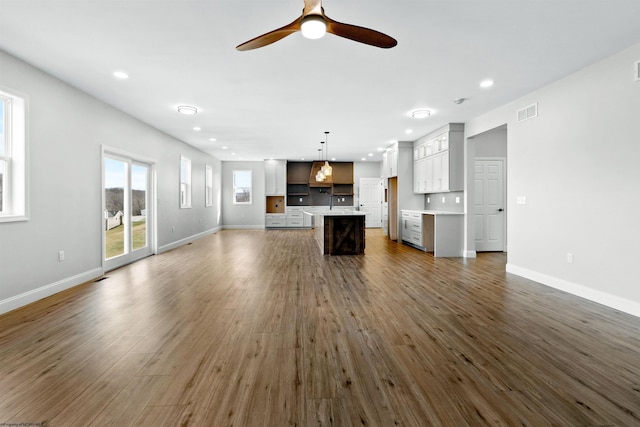 unfurnished living room with dark wood-type flooring, recessed lighting, and baseboards