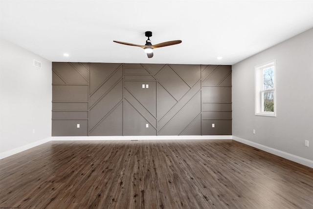 empty room featuring dark wood-style flooring, visible vents, ceiling fan, and baseboards