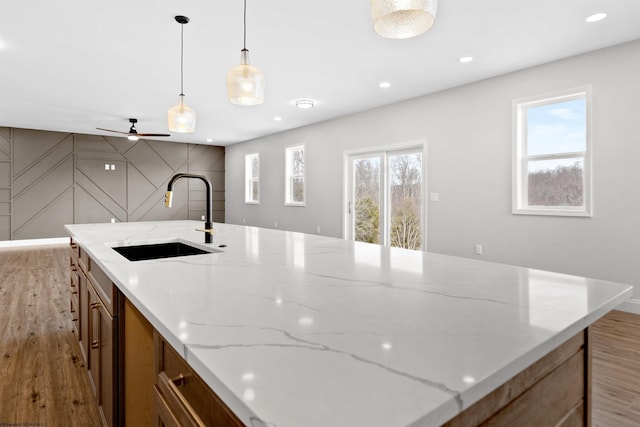 kitchen featuring light wood-style floors, recessed lighting, a healthy amount of sunlight, and a sink