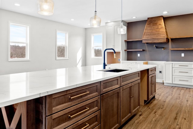 kitchen with light wood-type flooring, open shelves, a sink, and decorative light fixtures