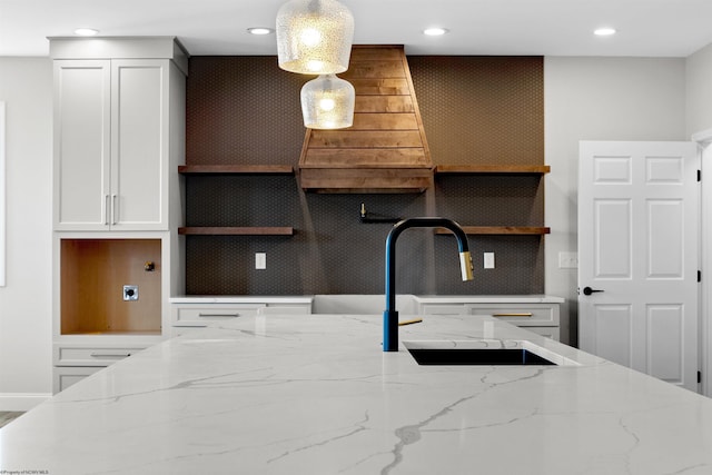 kitchen featuring light stone counters, white cabinetry, open shelves, and a sink