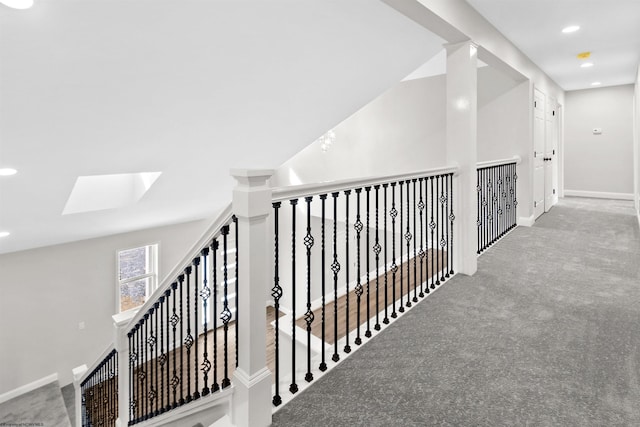 hallway featuring carpet, a skylight, baseboards, and recessed lighting