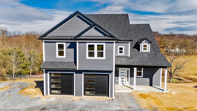 view of front of house featuring a garage, a shingled roof, gravel driveway, and fence