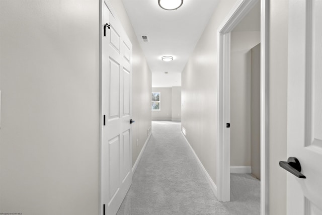 hall with light colored carpet, visible vents, and baseboards