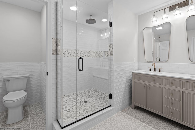 full bath featuring tile patterned flooring, wainscoting, tile walls, and toilet